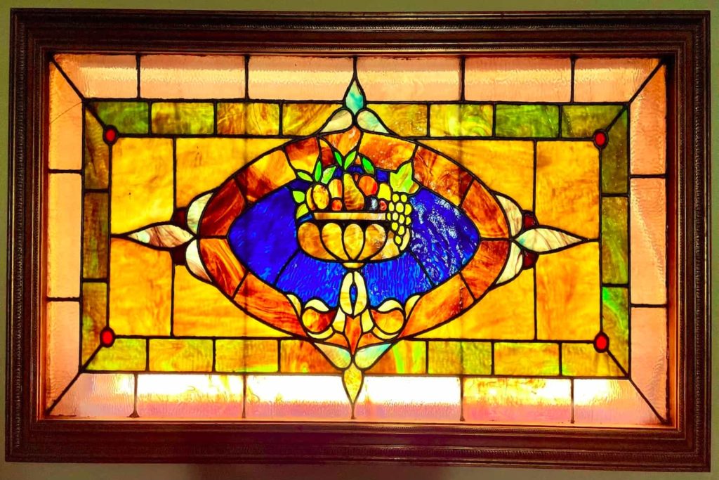 stained glass window featuring a bowl full of a variety of fruits.