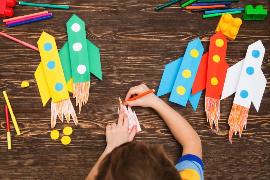 A child creating rocket ships out of colored paper.