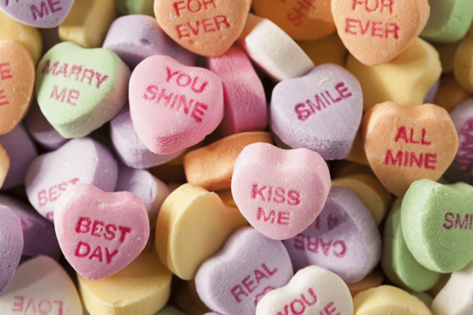 A pile of heart-shaped candies stamped with creative messages.