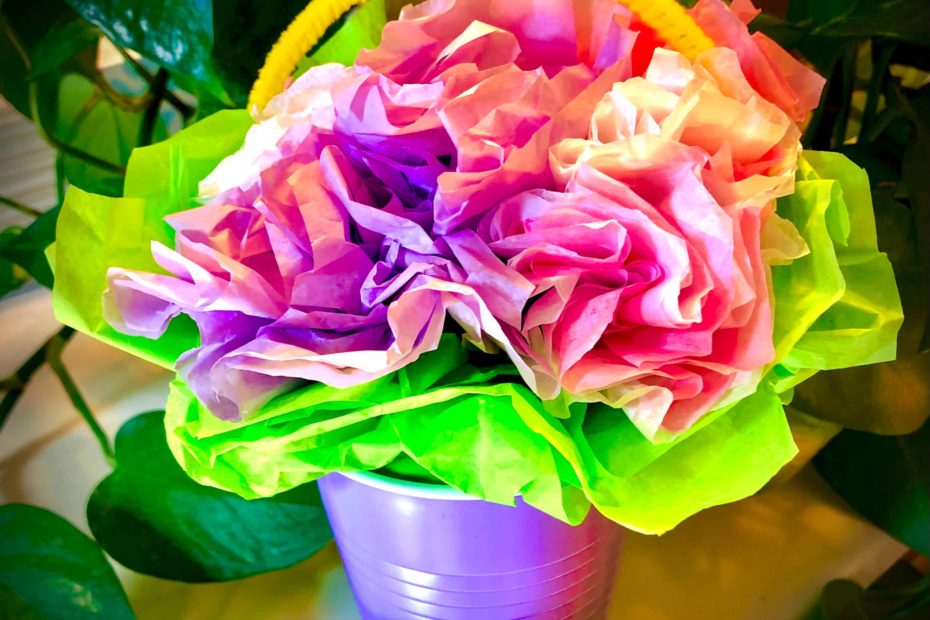 A home-crafted May basket made of a plastic cup and colorful tissue-paper flowers.