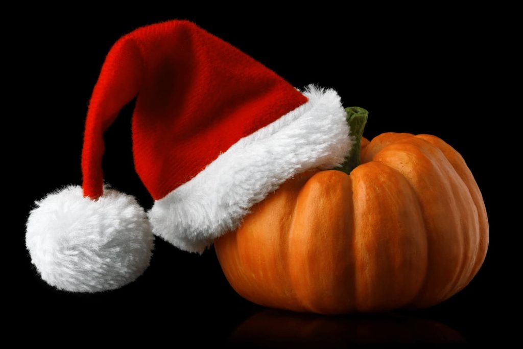 A creative placement of a Santa hat on a Halloween pumpkin.