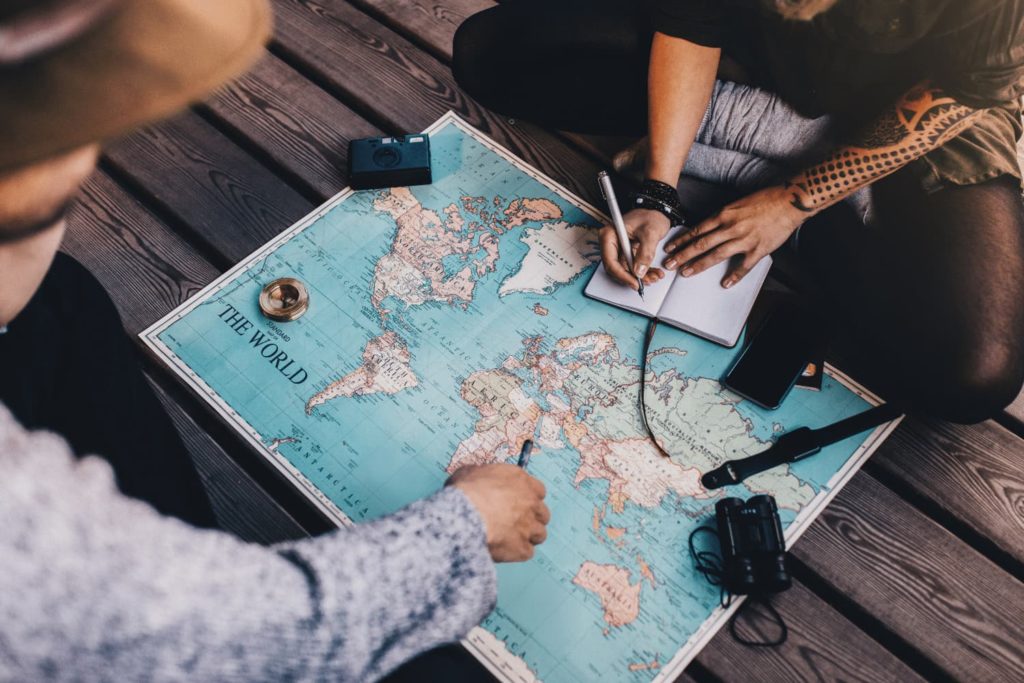 Two people sitting on the ground looking at a world map.