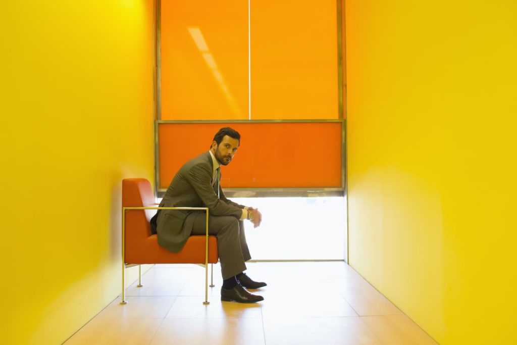 A businessman sitting alone in an orange and yellow interior.