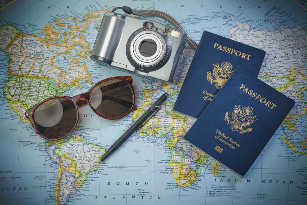 Two passports, sunglasses, and a camera spread out on a map.