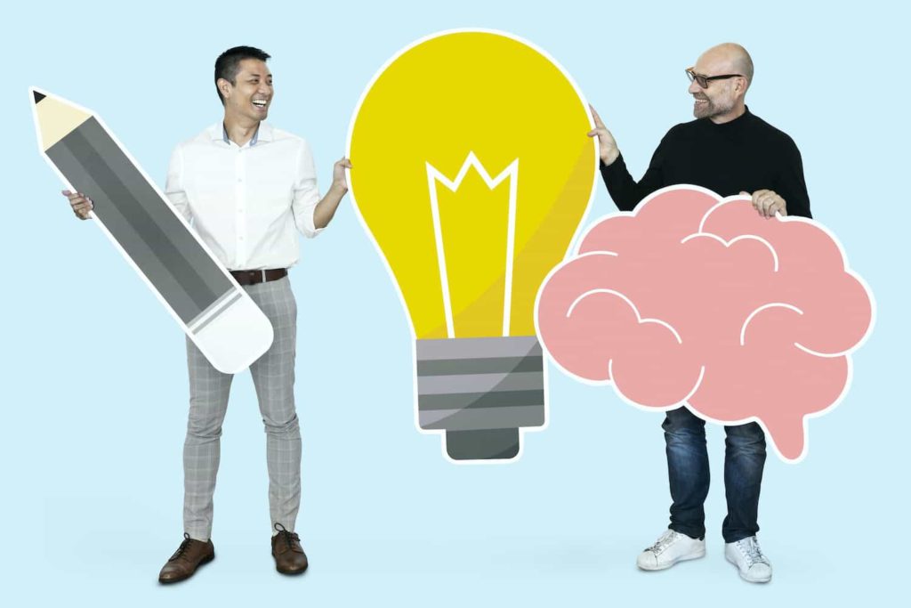 Two men holding up cardboard cutouts of a pencil, a lightbulb, and a brain.