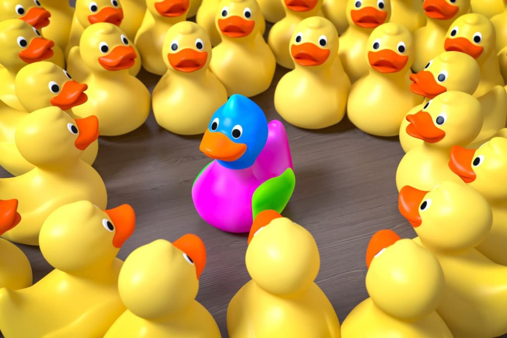 Many classic rubber duckies surrounding one brightly colored one.