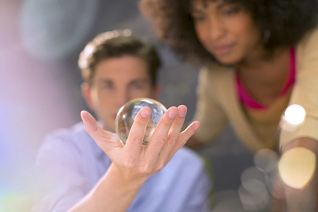 Two people examining a glass sphere held in the hand of one of them.