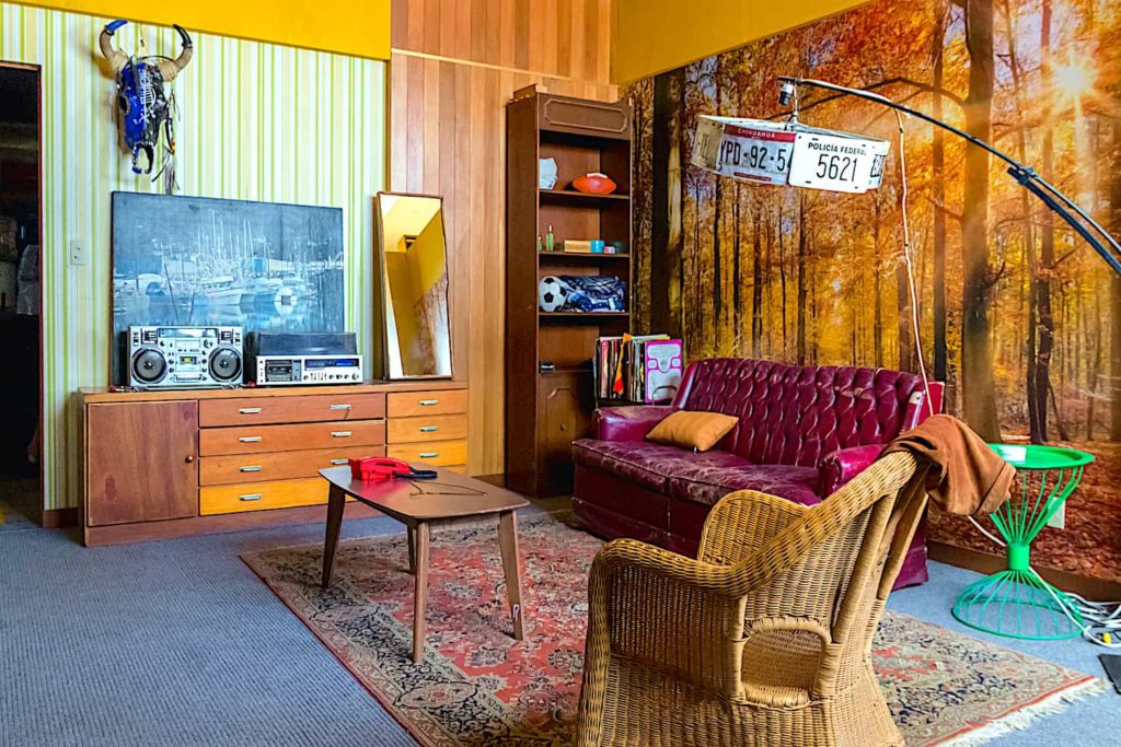 A vintage living room with wood paneling, a wallpaper mural, and colorful furnishings.