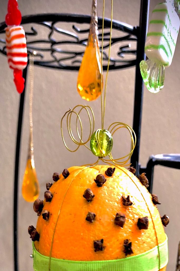 A pomander ball hanging with glass ornaments shaped like hard candy.