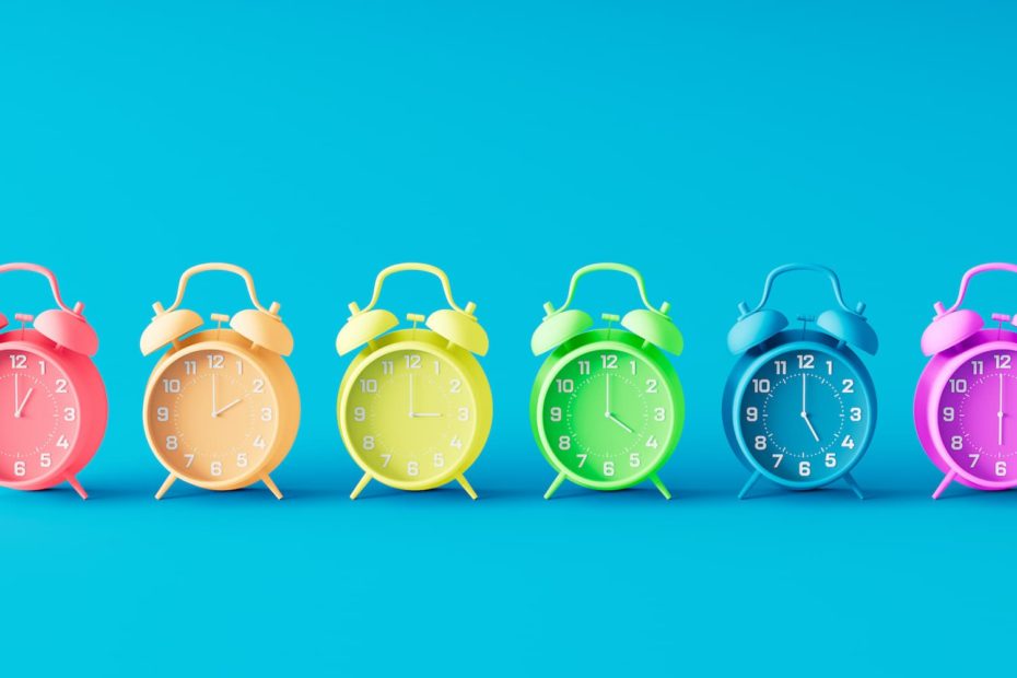 A line of clocks in six solid colors on a teal background.