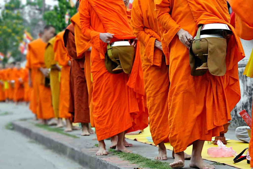 A photo of Buddhist monks in orange robes walking in a line.