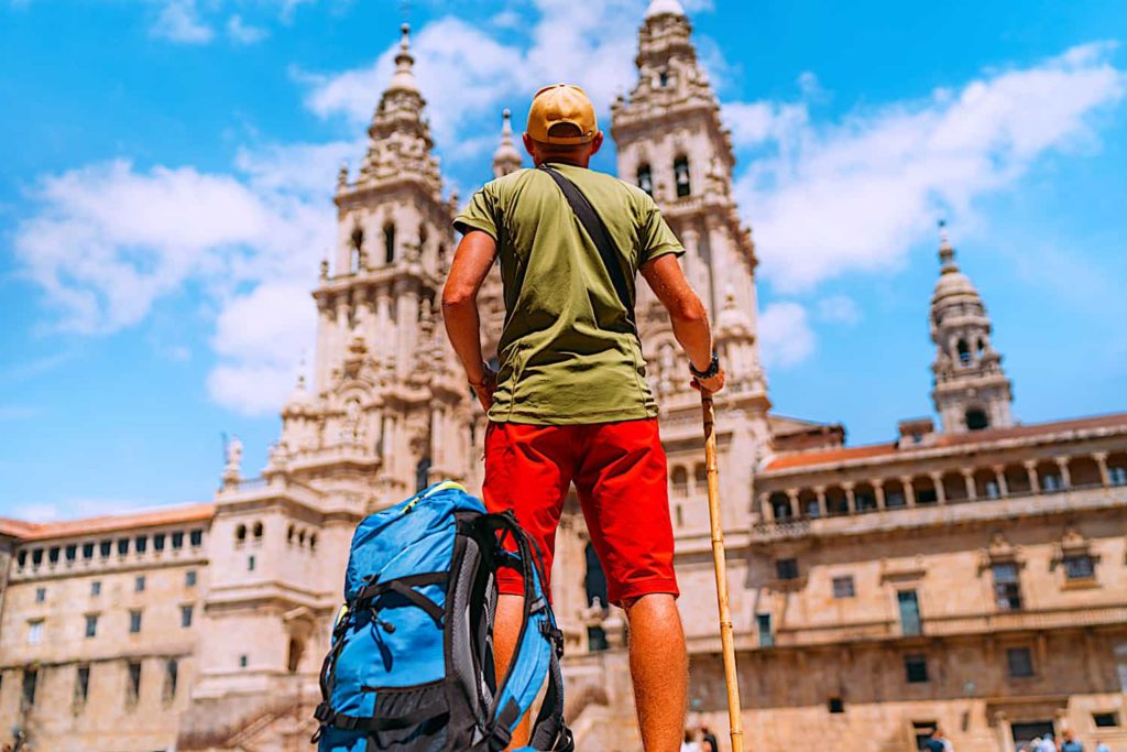 A modern pilgrim with a backpack facing the Cathedral of Santiago de Compostela.