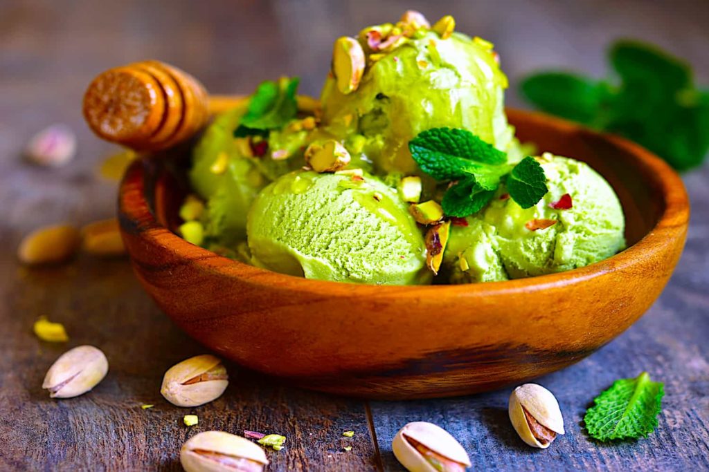 A wooden bowl of pistachio ice cream decorated with mint.